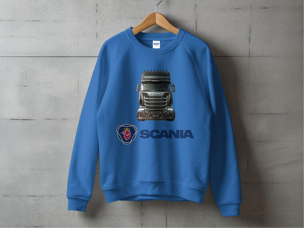 A blue graphic crewneck sweatshirt from Garment Graphics hangs on a wooden hanger against a concrete wall. It features a truck image and the bold Scania logo, ideal for truck enthusiasts.