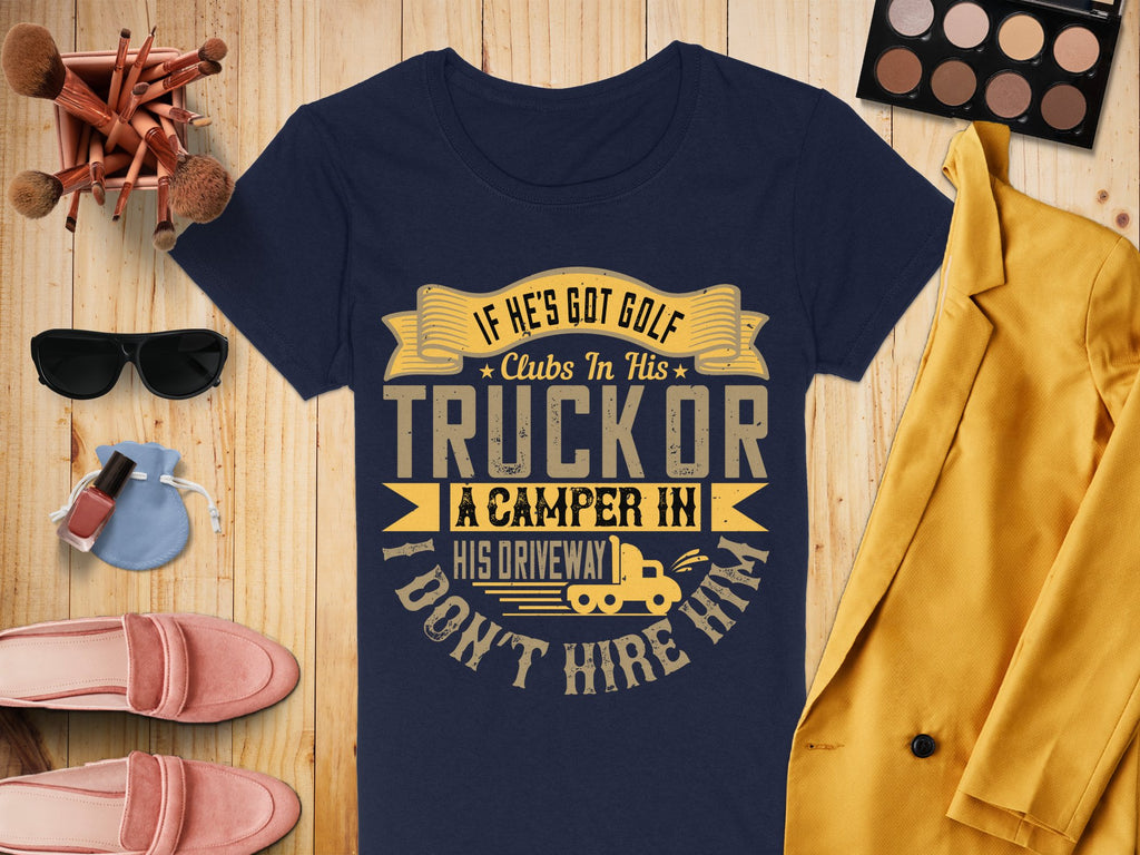 A flatlay features a quirky navy T-shirt from Garment Graphics with the funny golf quote, paired expertly with makeup brushes, an eyeshadow palette, a yellow coat, shoes, perfume, and a camera. Its available in womens sizes.