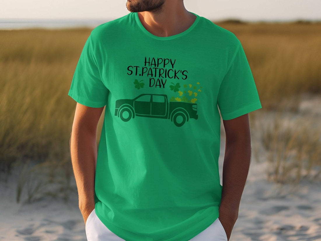 A man in a Garment Graphics green T-shirt with Happy St. Patricks Day proudly showcases Irish pride alongside a truck adorned with shamrocks, set against a sandy backdrop with grass, creating a festive atmosphere.
