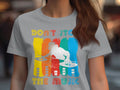 A music enthusiast sports a light gray DJ graphic tee from Garment Graphics, featuring dynamic vertical paint streaks in red, yellow, blue, and green with a central white silhouette of a DJ at turntables. The text reads Dont Stop the Music.