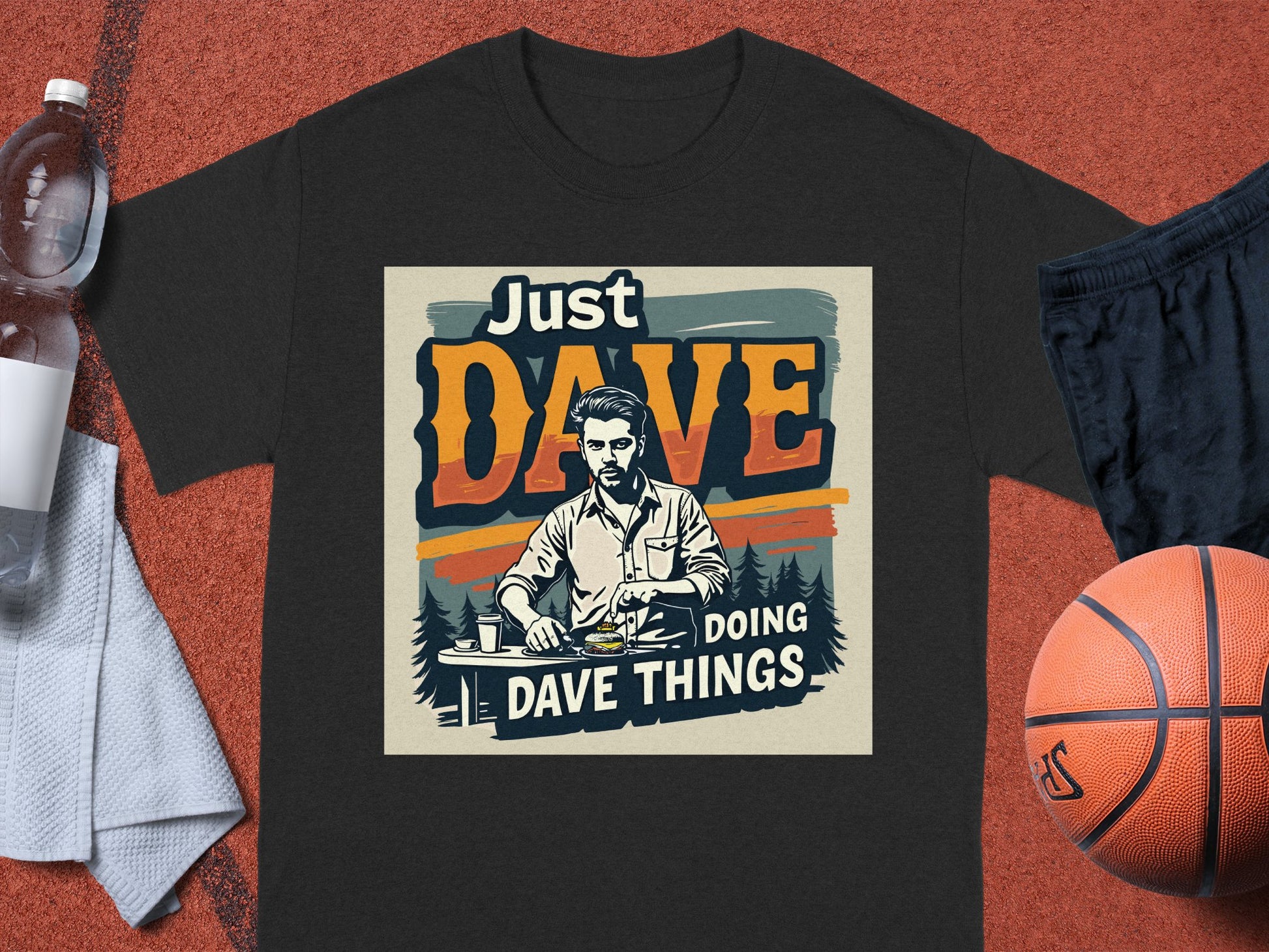 Garment Graphics classic fit T-shirt features Just Dave Doing Dave Things above a seated man illustration. Its on a sports court with items like a basketball, black shorts, water bottle, and white towel. Ideal for those who live by their own playbook.