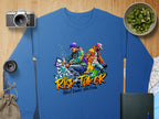 Garment Graphics blue sweatshirt showcases two street dancers in vibrant outfits with graffiti accents and Risk Taker Street Dance Finals text. Nearby are a camera, cucumber bowl, lenses, map, bag, and book. Ideal for anyone embracing street dances bold energy.