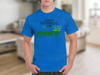 Wearing a Garment Graphics blue T-shirt with Happy St. Patricks Day and a green pickup truck filled with shamrocks, the person displays Irish pride, enhanced by a blurred room background for a festive vibe.