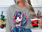 A person dons a Garment Graphics sweatshirt with a unicorn and I Love My Pony text, while holding a Santa-themed mug against a festively decorated white wall.