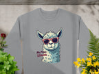 The Garment Graphics No Prob-Llama sweatshirt in gray features a playful llama with pink sunglasses and No Prob-llama text. It has a unisex fit and is styled against a concrete background with green and yellow plants.