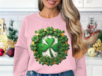 Amid festive kitchen decor, a woman showcases her Irish spirit with a pink Garment Graphics sweatshirt featuring a lucky four-leaf clover surrounded by smaller ones. Her long, wavy hair cascades as she smiles, savoring the charm of the moment.