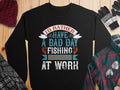 Garment Graphics presents a black unisex fishing sweatshirt with Id rather have a bad day fishing than a good day at work in mixed fonts and colors. Styled with a red beanie, plaid shirt, striped gloves, and glasses on wood—ideal for passionate fishers.