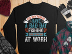 Garment Graphics presents a black unisex fishing sweatshirt with Id rather have a bad day fishing than a good day at work in mixed fonts and colors. Styled with a red beanie, plaid shirt, striped gloves, and glasses on wood—ideal for passionate fishers.