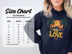 A woman wears a Garment Graphics navy hoodie featuring a tropical sunset, palm trees, and One Love. Next to her is a Gildan 18500 size chart for sizes Small to 5XL with width and length in inches. Embrace your unique style with this graphic hoodie.