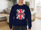 A person is wearing a unisex navy blue Garment Graphics sweatshirt with the UK flag and text: Dont Blame Me I Didnt Vote For Him, set against a softly blurred indoor background.
