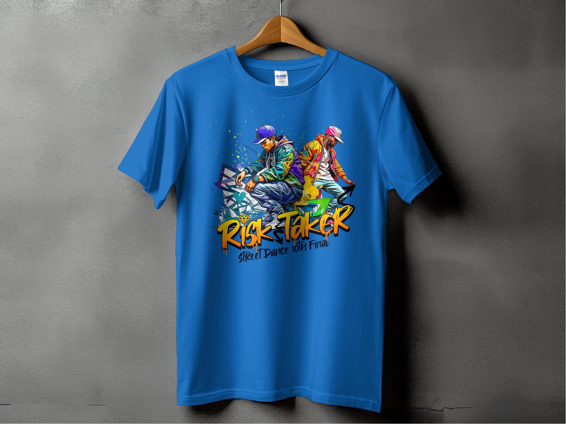 A blue t-shirt from Garment Graphics exclusive Risk Taker 10th Final T-Shirts collection is displayed on a hanger, featuring artistic designs of two stylized dancers in vibrant outfits. It celebrates street dance culture with Risk Taker and Street Dance with Fire boldly printed below.