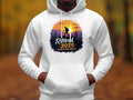 A person wears a Garment Graphics white hiking hoodie featuring a sunset mountain design with a hiker silhouette, combined with the phrase Retired 2025, Not My Problem Anymore set against an autumn forest with softly blurred trees.