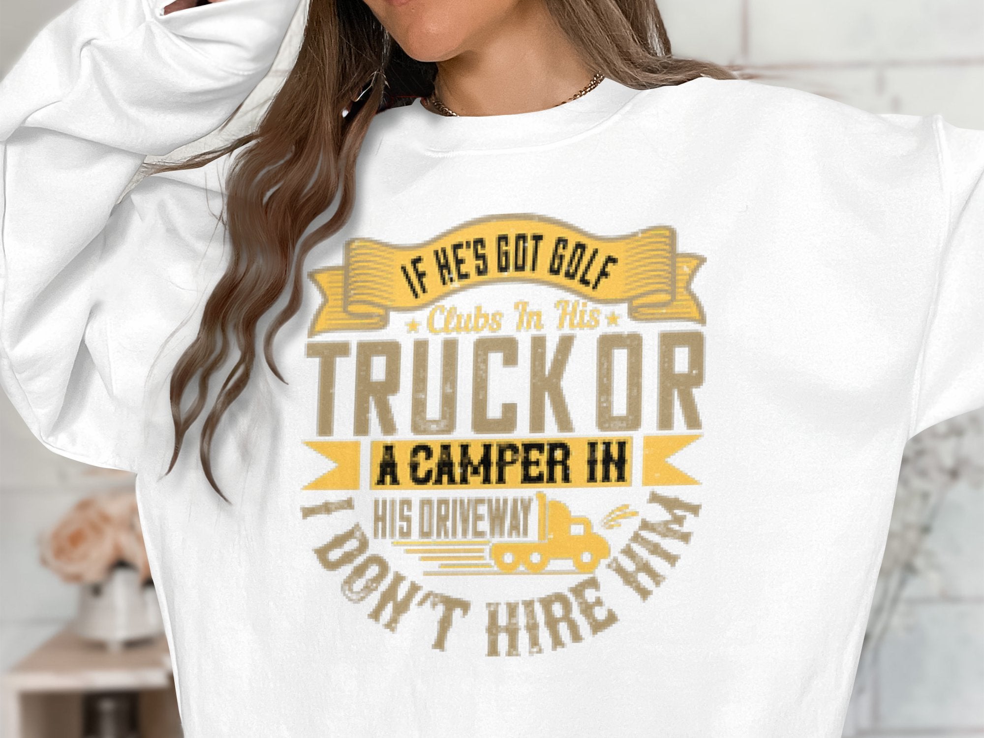 A person is wearing a white sweatshirt from Garment Graphics, featuring a witty graphic and the phrase: If hes got golf clubs in his truck or a camper in his driveway, dont hire him, enhanced with unique designs of a golf club and camper.