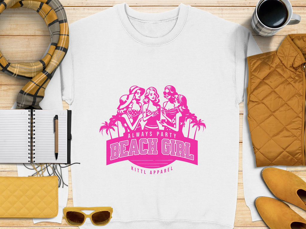 A Garment Graphics white t-shirt with a pink design featuring three women, palm trees, and Always Party Beach Girl. Its stylishly displayed on wood, surrounded by a scarf, notebook, mug, jacket, wallet, and sunglasses.
