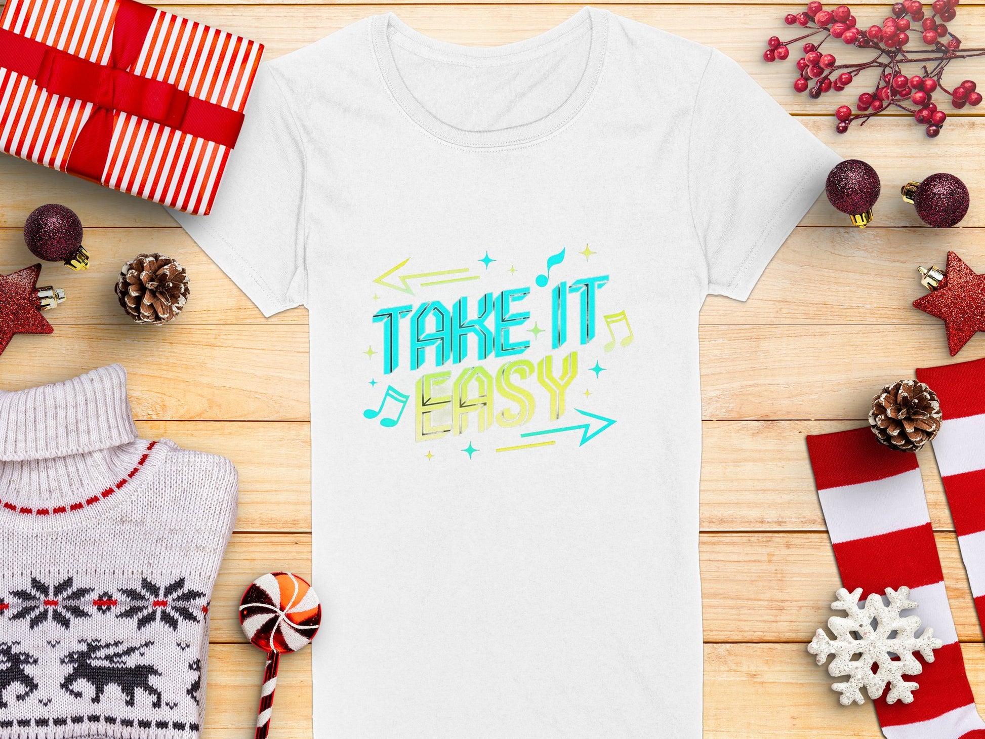 Amidst holiday-themed items like gifts and ornaments, a white T-shirt from Garment Graphics sits on a wooden surface, adorned with vibrant TAKE IT EASY graphics in blue and yellow, surrounded by musical notes and arrows—a perfect addition to the festive season.
