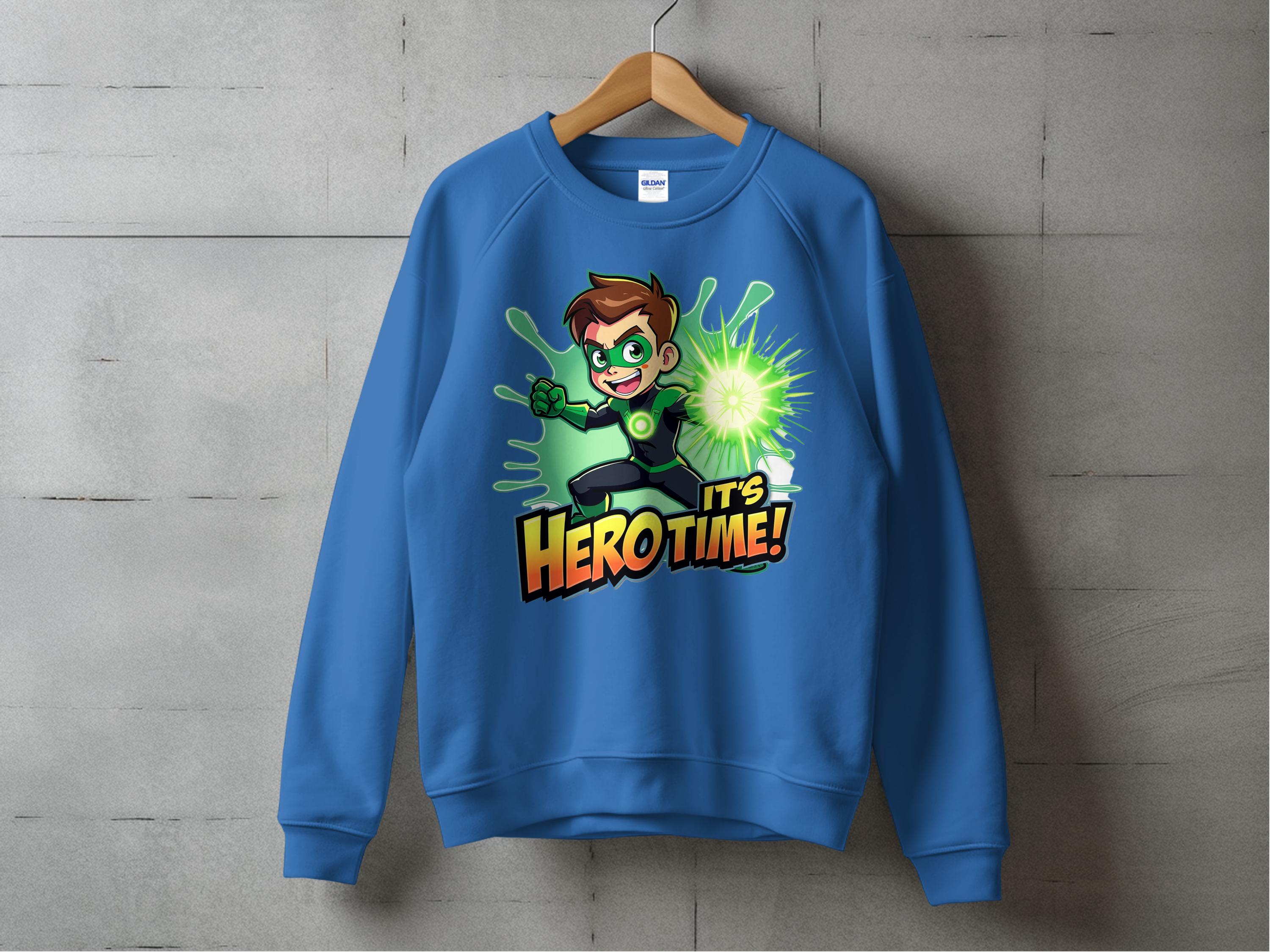 A blue cartoon-themed sweatshirt from Garment Graphics hangs against a concrete wall, featuring an animated character with brown hair and green eyes wielding a glowing green power. The bold words Its Hero Time! complete the print. Available in unisex sizing for every hero at heart.