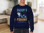 Someone wears a Garment Graphics navy blue fishing sweatshirt with Daddys Fishing Buddy, featuring a fish and boat design. The softly blurred interior background sets the scene for fishing enthusiasts cherishing their bond on the water.