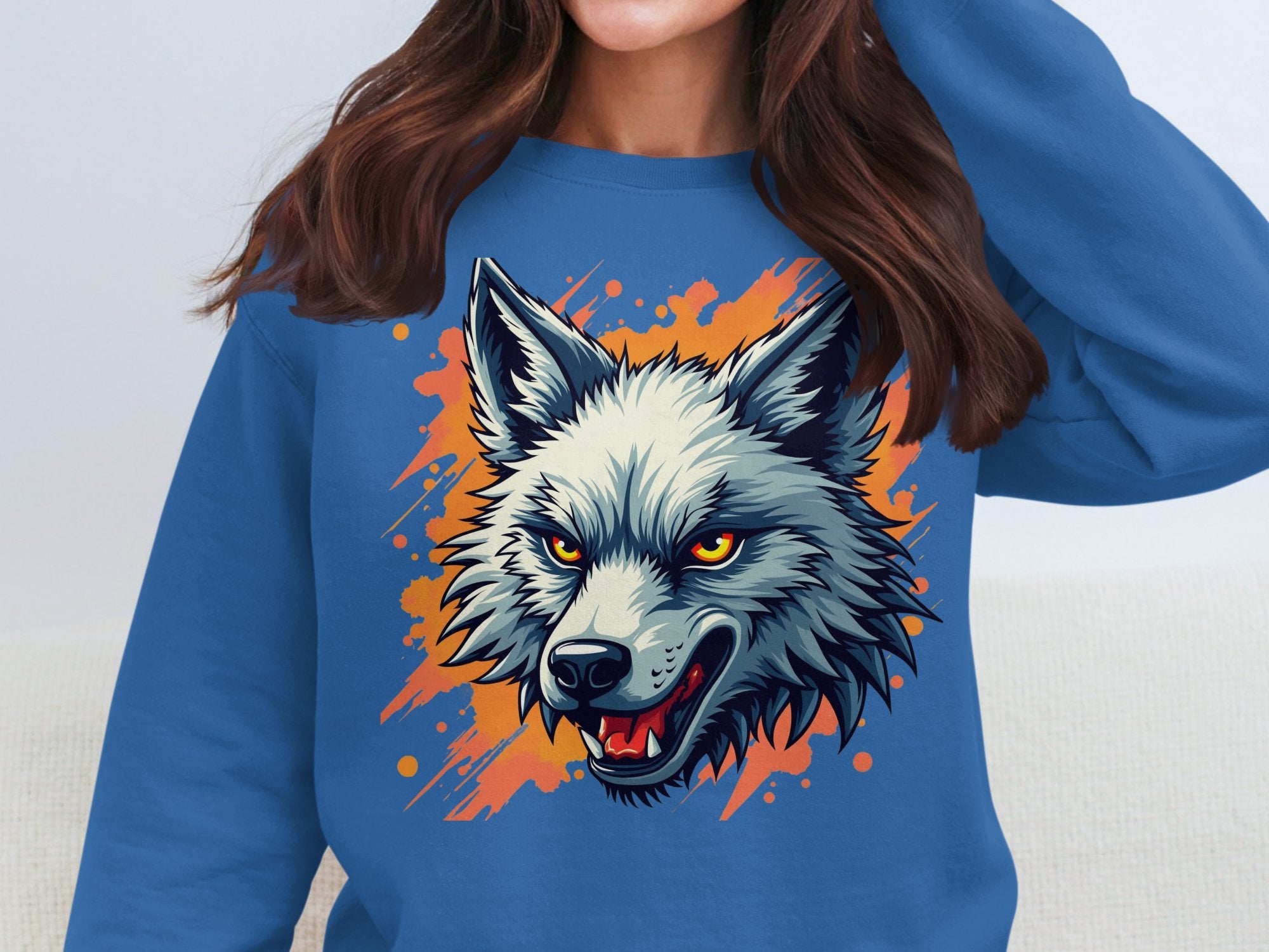 Someone is donning Garment Graphics fierce blue wolf graphic sweatshirt, making a bold statement. The design features a wolfs head with wild orange accents, piercing yellow eyes, and an open mouth with sharp teeth, while the persons face remains hidden.