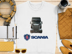 Garment Graphics offers a graphic crewneck sweatshirt with a detailed Scania truck illustration above its iconic logo. This cozy piece is styled on a wooden surface and complemented by accessories like a scarf, coffee cup, quilted jacket, notebook with pen, yellow clutch, and sunglasses. Perfect for truck enthusiasts!.