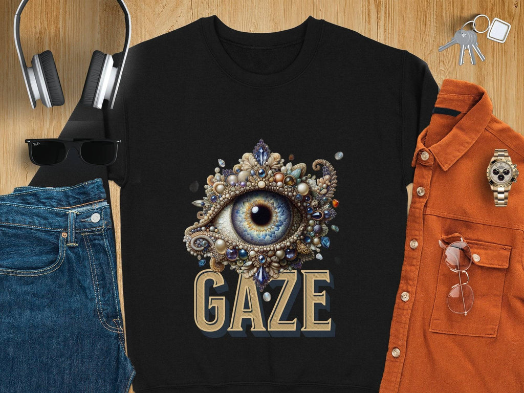 On a wooden surface, a Garment Graphics unisex black t-shirt with an eye design and the word GAZE is styled with jeans, headphones, sunglasses, an orange shirt, a watch, and keys—ideal for any wardrobe.