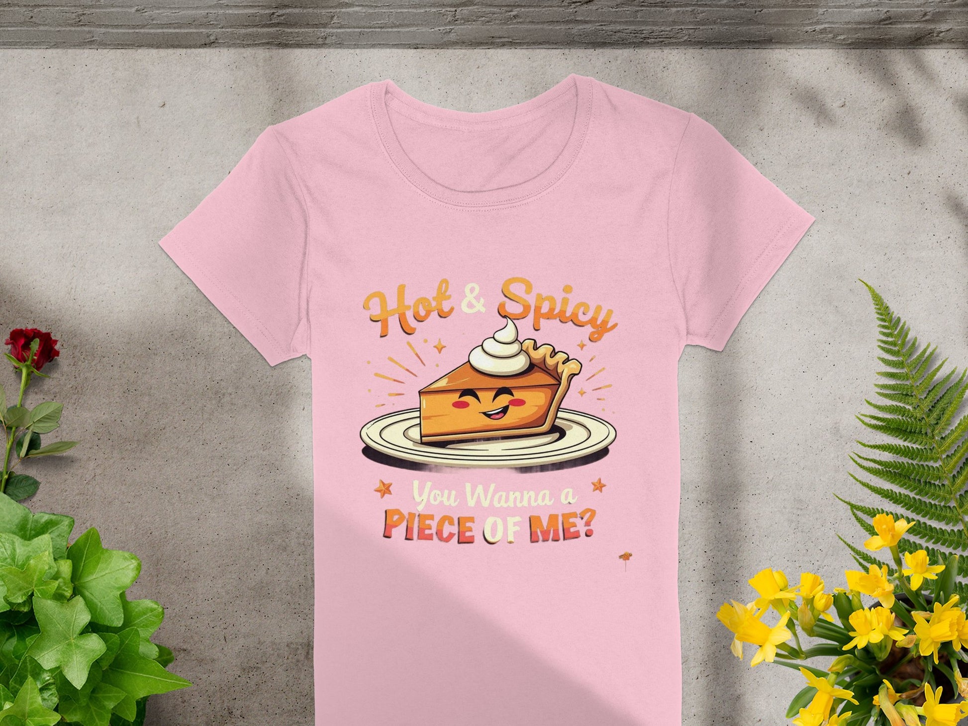 This Garment Graphics pink womens T-shirt features a playful illustration of a smiling pie slice with whipped cream. The text reads Hot & Spicy above and You Wanna a Piece of Me? below, with red and yellow flowers adding flair to the gray background, perfect for casual outings.
