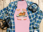 A Garment Graphics plaid shirt, a pink T-shirt with Hot & Spice, You Wanna a Piece of Me? graphic, headphones, and a camera lie on wood. Perfectly sized for women and ideal for casual outings.