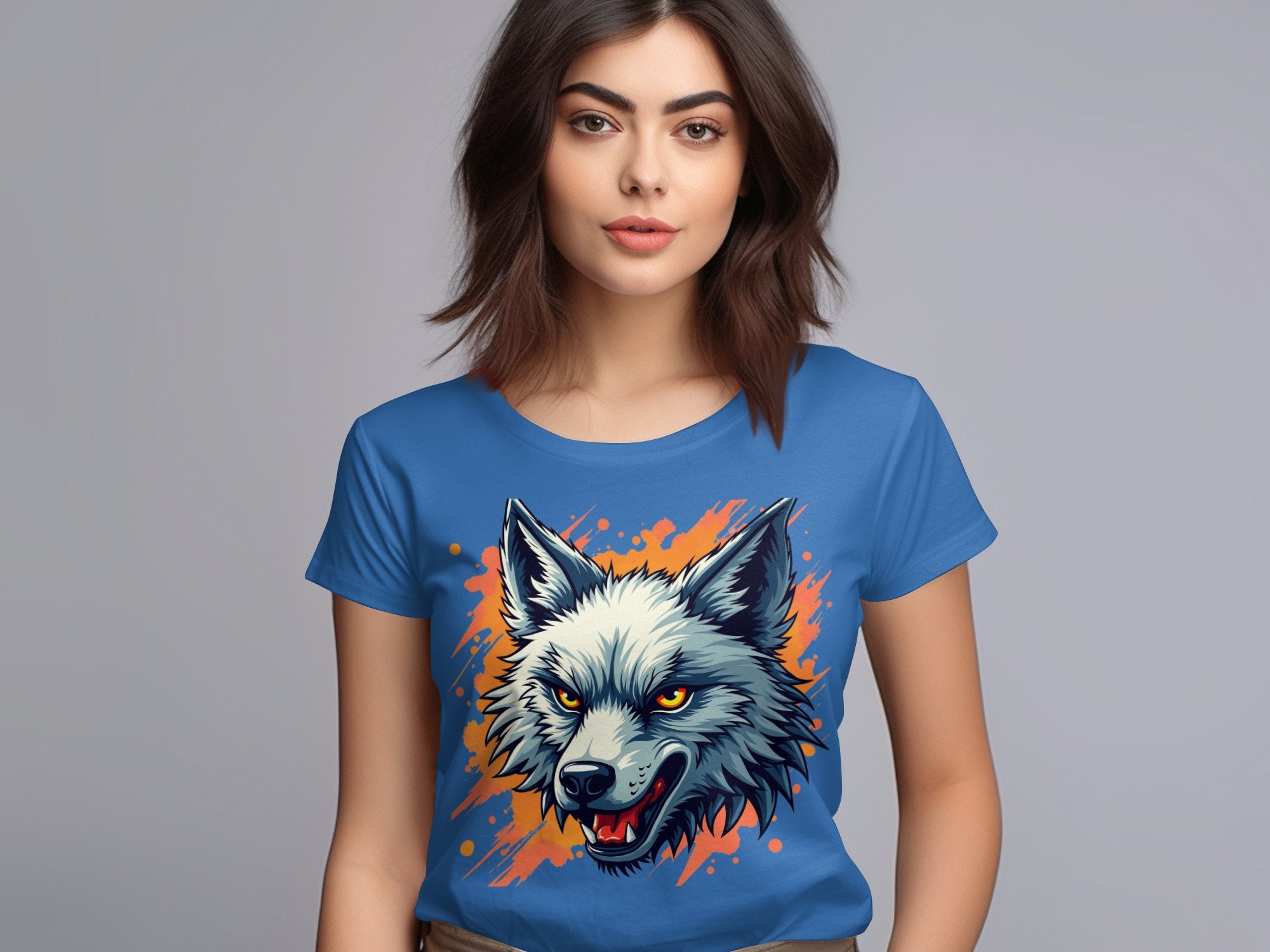 A woman with brown hair wears a bold wolf print T-shirt from Garment Graphics. The 100% cotton shirt features a wolfs head with an open mouth, surrounded by orange splashes on a plain gray background, creating a vibrant design.