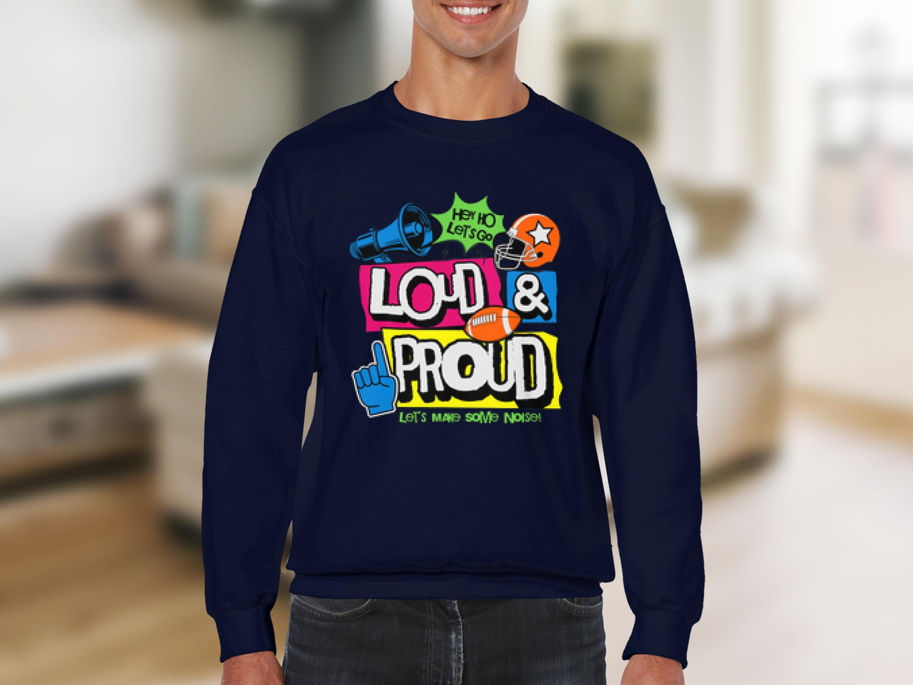 Someone wearing a Garment Graphics dark blue unisex sweatshirt with vibrant designs and the text LOUD & PROUD, featuring a megaphone, symbols, and phrases like Hey Yo Lets Go and Lets Make Some Noise! stands out uniquely against a blurred indoor background.