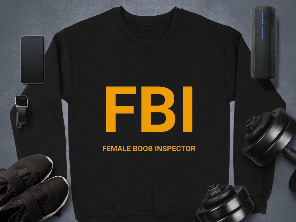 Garment Graphics black sweatshirt with bold yellow FBI lettering and the phrase Female Boob Inspector in unisex sizing is the standout piece among a smartphone, smartwatch, sneakers, portable speaker, and adjustable dumbbells.