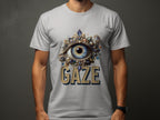Wearing a classic fit light gray graphic T-shirt by Garment Graphics, the person features an intricate eye gaze design with ornate embellishments. GAZE is boldly printed below the eye. Complemented by a wristwatch, they maintain a neutral pose.