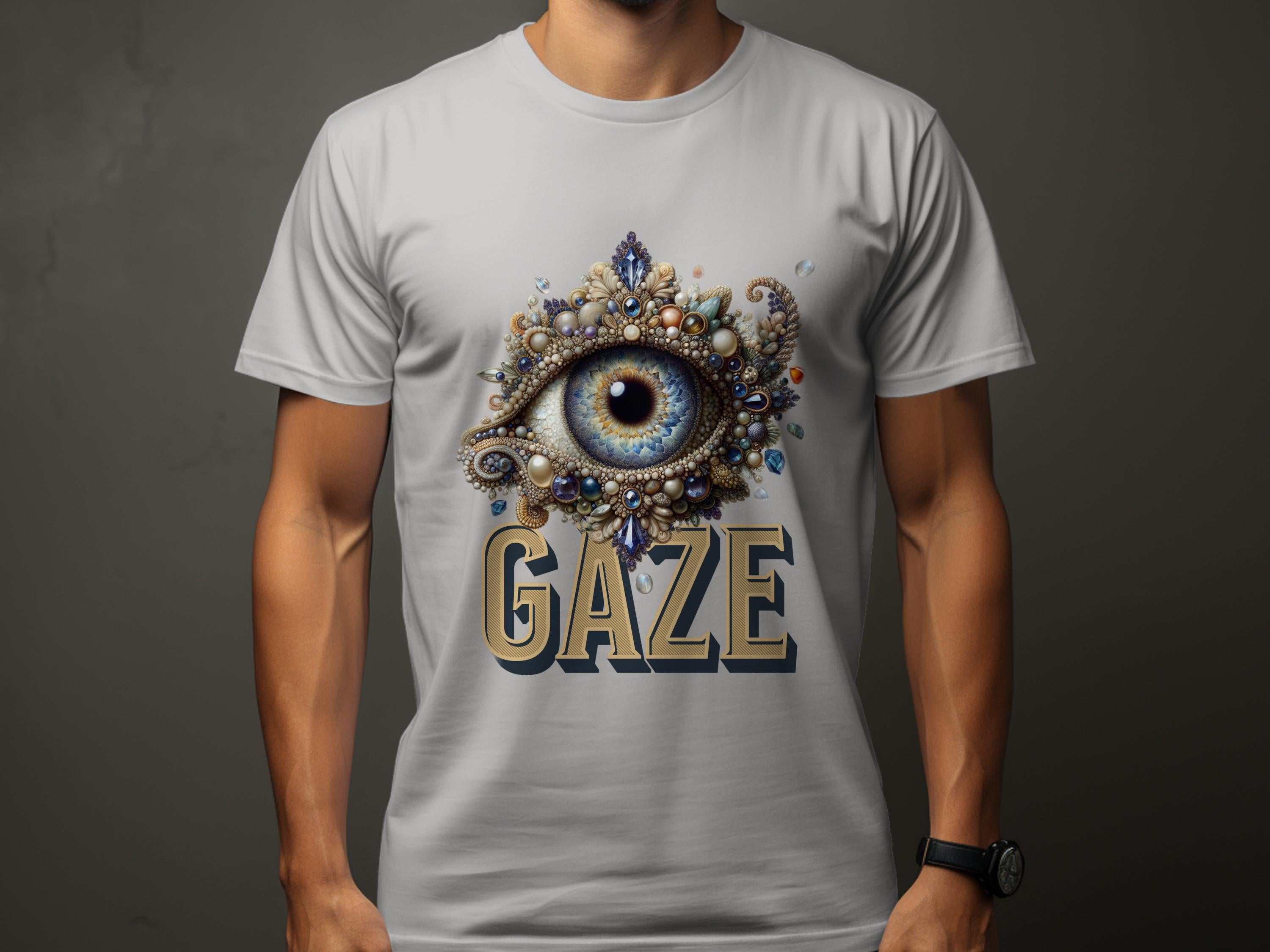 Wearing a classic fit light gray graphic T-shirt by Garment Graphics, the person features an intricate eye gaze design with ornate embellishments. GAZE is boldly printed below the eye. Complemented by a wristwatch, they maintain a neutral pose.