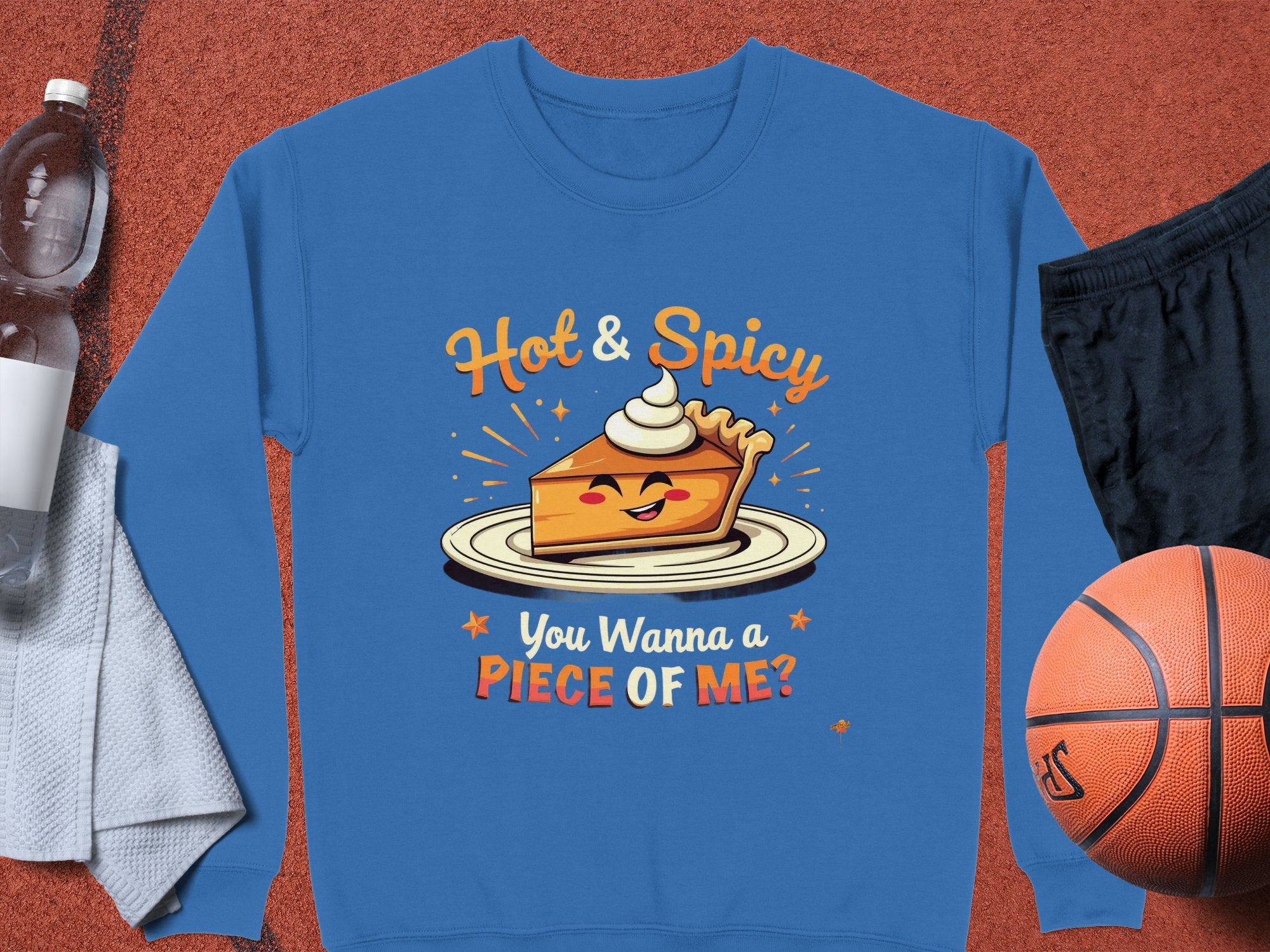 This unisex Hot & Spicy sweatshirt by Garment Graphics features a cheerful pie with whipped cream and reads, You Wanna a Piece of Me? Its styled with a towel, water bottle, black shorts, and basketball for an energetic vibe.