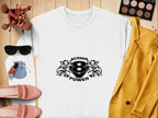 A stylish white Garment Graphics sweatshirt with a cool print of two lions and Scania Power V8 lies on a wooden surface, surrounded by a yellow blazer, pink loafers, sunglasses, makeup brushes, an eyeshadow palette, and perfume.
