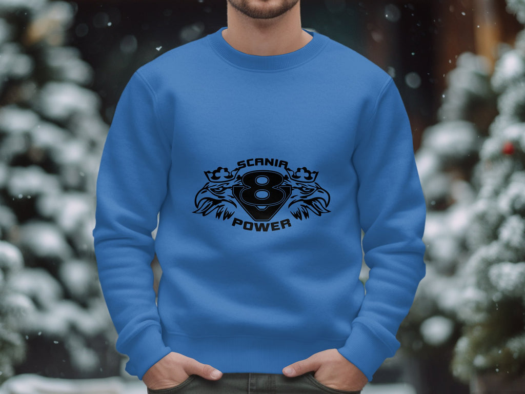 A person wears a blue sweatshirt by Garment Graphics, featuring the Scania Power 8 logo with stylized lions. Snow-covered trees and a gentle bokeh effect in the background capture the serene essence of winter.
