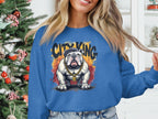 Wearing a Garment Graphics Bulldog Sweatshirt in blue, featuring a bulldog graphic with a cap and gold chain and surrounded by CITY KING, a person stands before a decorated Christmas tree.
