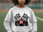 Against a blurred outdoor green surface, a person wears a vibrant Garment Graphics sweatshirt featuring a red racing car and black and white checkered flags. Ideal for motorsport enthusiasts, the persons face is partially visible.