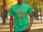 A person is outdoors in a Garment Graphics tee with Running on Grace & Coffee in orange text. The blurred park background, with autumn trees, creates an uplifting vibe that matches the inspirational quotes essence.