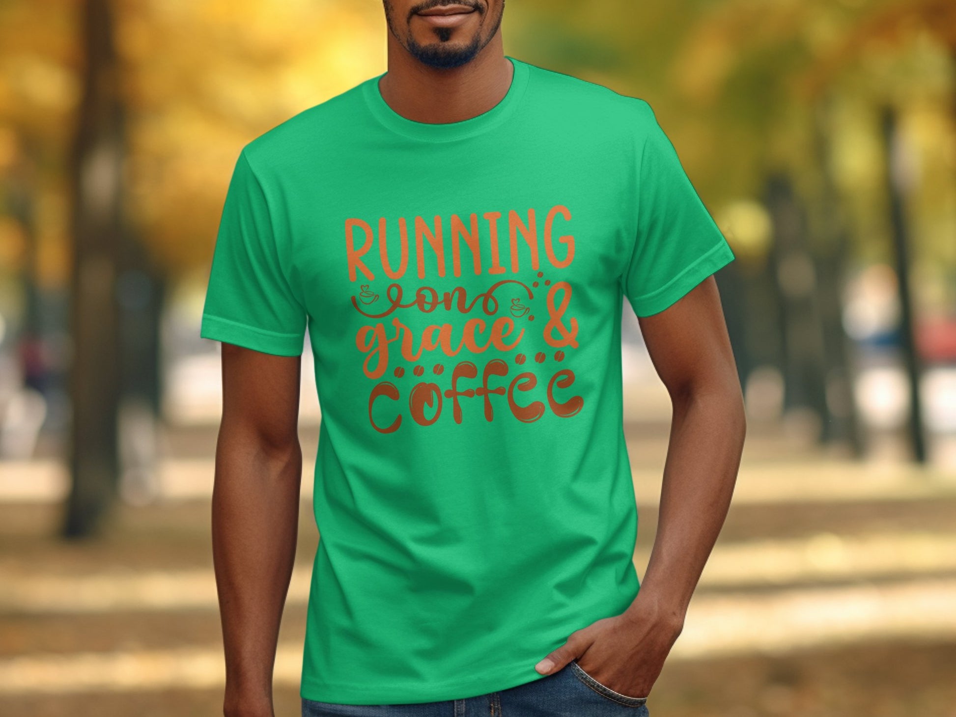 A person is outdoors in a Garment Graphics tee with Running on Grace & Coffee in orange text. The blurred park background, with autumn trees, creates an uplifting vibe that matches the inspirational quotes essence.