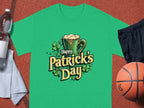 Garment Graphics Happy Patricks Day T-shirt with shamrock graphics stands out on an orange sports court. Pair it with a water bottle, white towel, black shorts, and a basketball for a festive and active day.