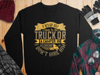A black Garment Graphics sweatshirt with the text, If hes got golf clubs in his truck or a camper in his driveway, I dont hire him, along with golf cart and camper images, is on a wooden surface. Nearby are a maroon knit hat, gloves, and plaid shirt.