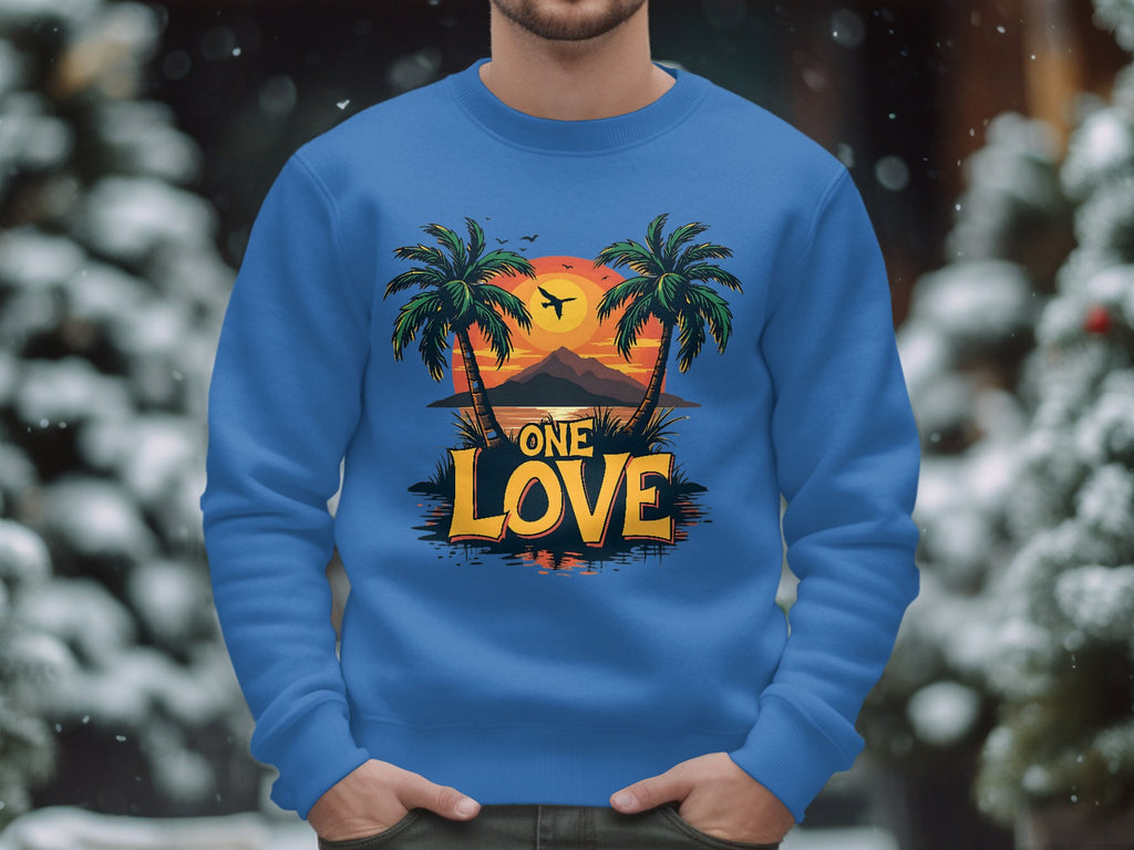 Garment Graphics offers a unisex blue One Love Sweatshirt featuring a tropical sunset with palm trees, a plane, and mountains. The words One Love stand out boldly as snow-covered trees blur in the background.
