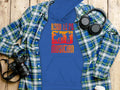 Garment Graphics blue hoodie features Born to Be a Musician with a drum set design, ideal for music lovers and unisex fashion fans. Displayed on wood, its accented by a plaid shirt, over-ear headphones, camera, and white to-go cup.