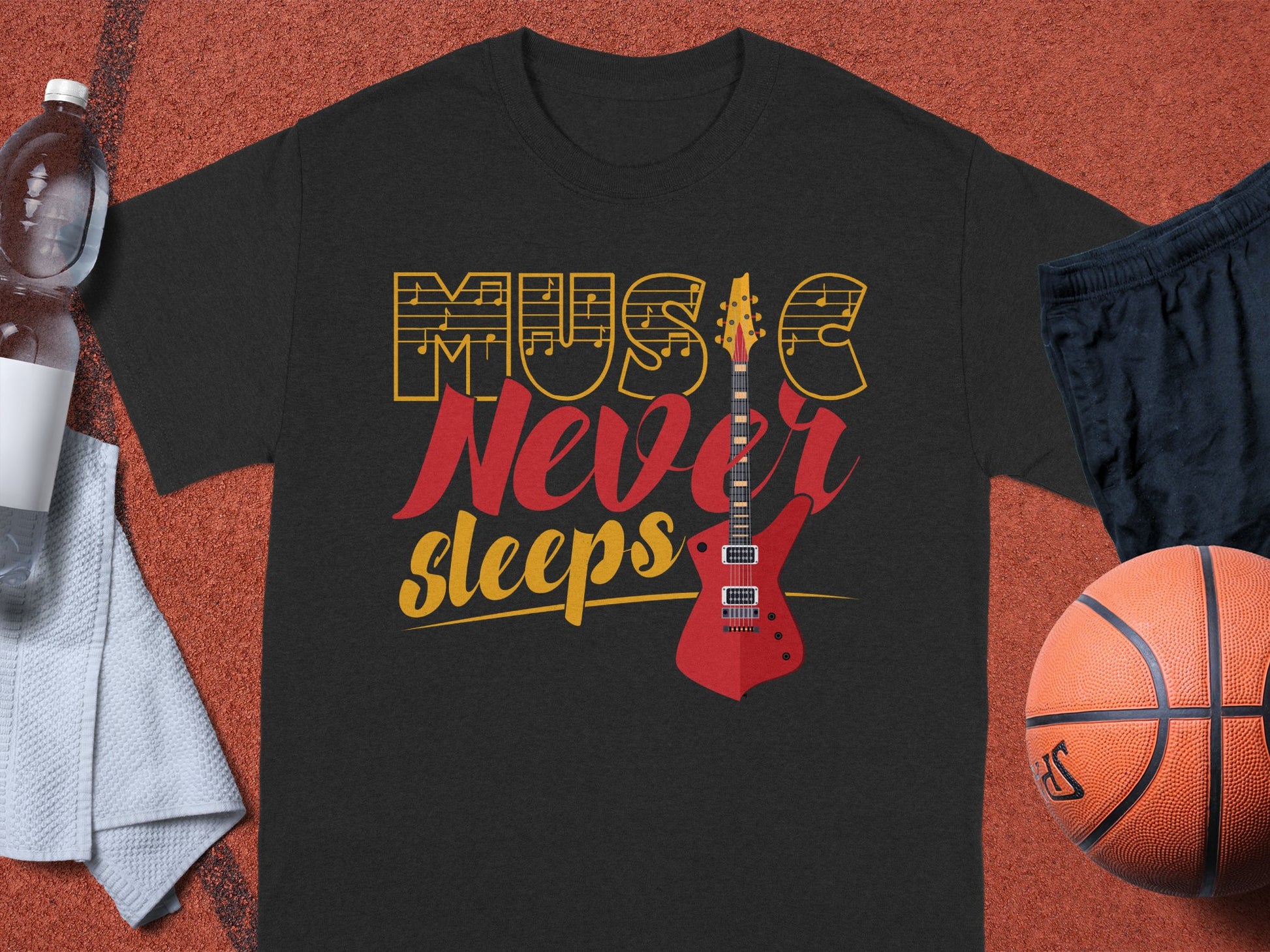 A Garment Graphics 100% cotton black T-shirt showcases Music Never Sleeps with a red electric guitar design. Displayed on red, it pairs perfectly with a water bottle, white towel, black shorts, and basketball—ideal for music-loving athletes.