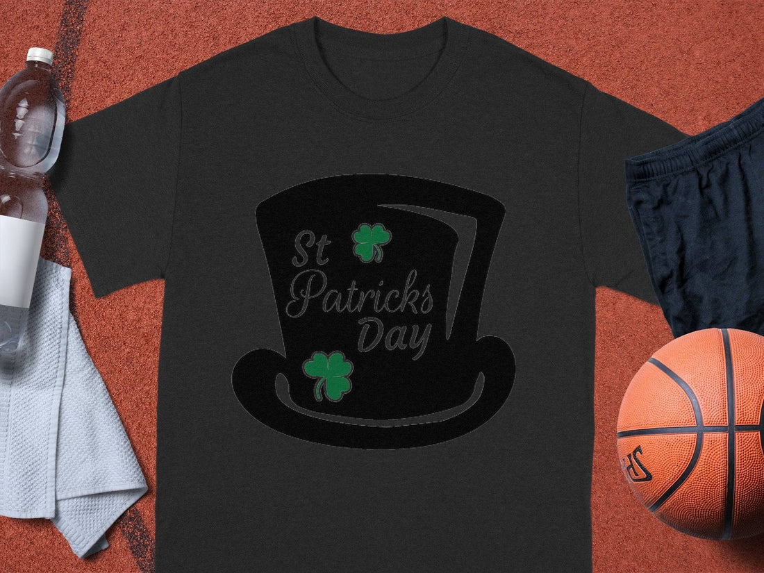 Garment Graphics white T-shirt features St. Patricks Day text, a black top hat, and two green shamrocks reminding of a four-leaf clover, against a gray background—ideal for festivities.
