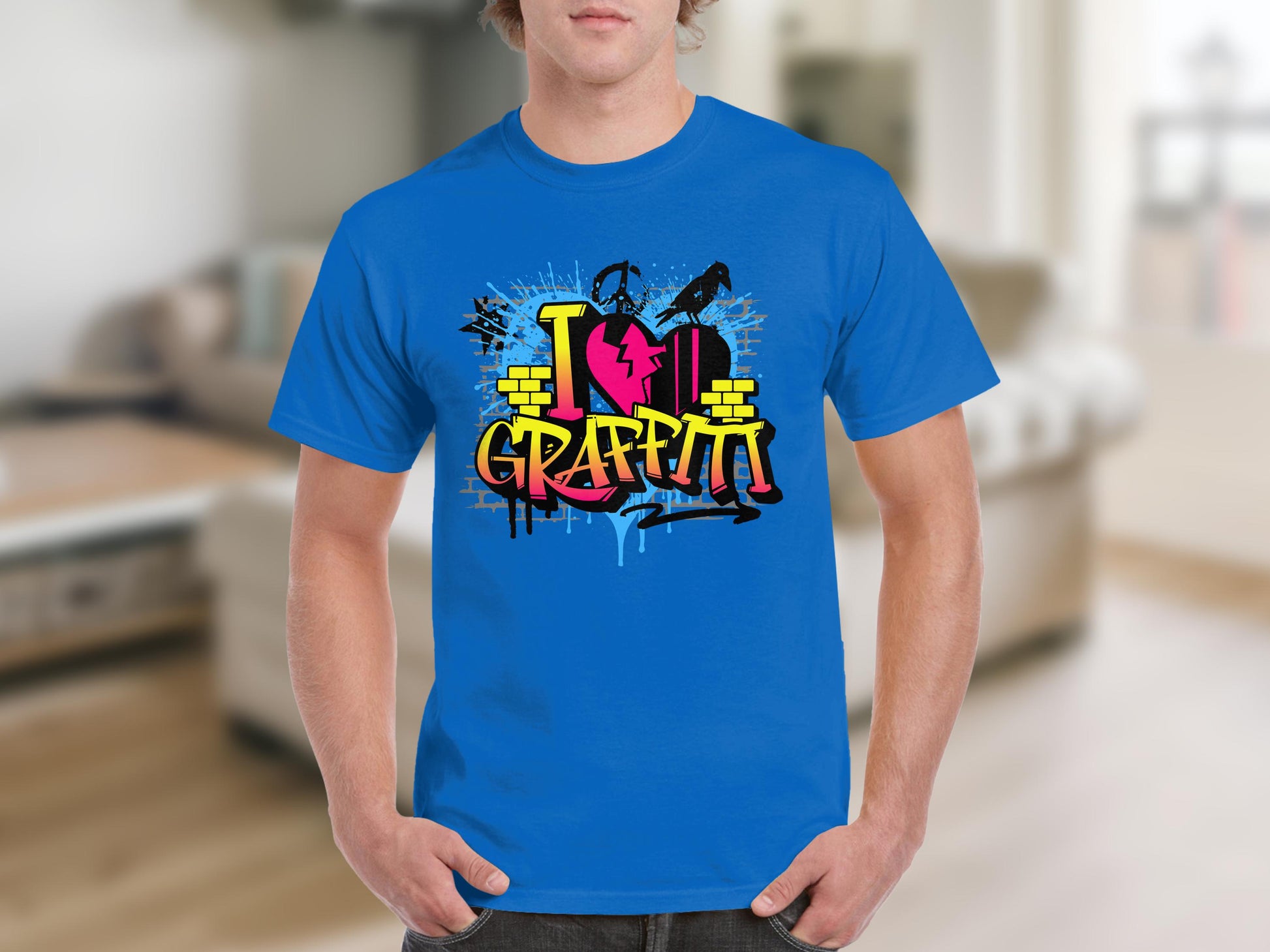 Sporting a vibrant Garment Graphics Graffiti Love T-Shirt, the person in the blurred indoor setting wears a blue tee adorned with colorful graffiti-style text, I Love Graffiti, and a spray paint can design, perfectly capturing street arts essence.