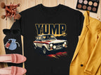 A black YUMP design rally car graphic T-shirt by Garment Graphics is on a wooden surface. Nearby are a yellow blazer, sunglasses, makeup palette with brushes, pink shoes, lip products, and a blue pouch. Ideal for pairing with trendy sweatshirts for casual outings.