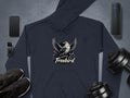 A Garment Graphics Freebird Graphic Pullover Hoodie, showcasing a bird with open wings, is laid out on a gray surface with a smartphone, smartwatch, wireless speaker, sneakers, and dumbbells to complete the unique style.