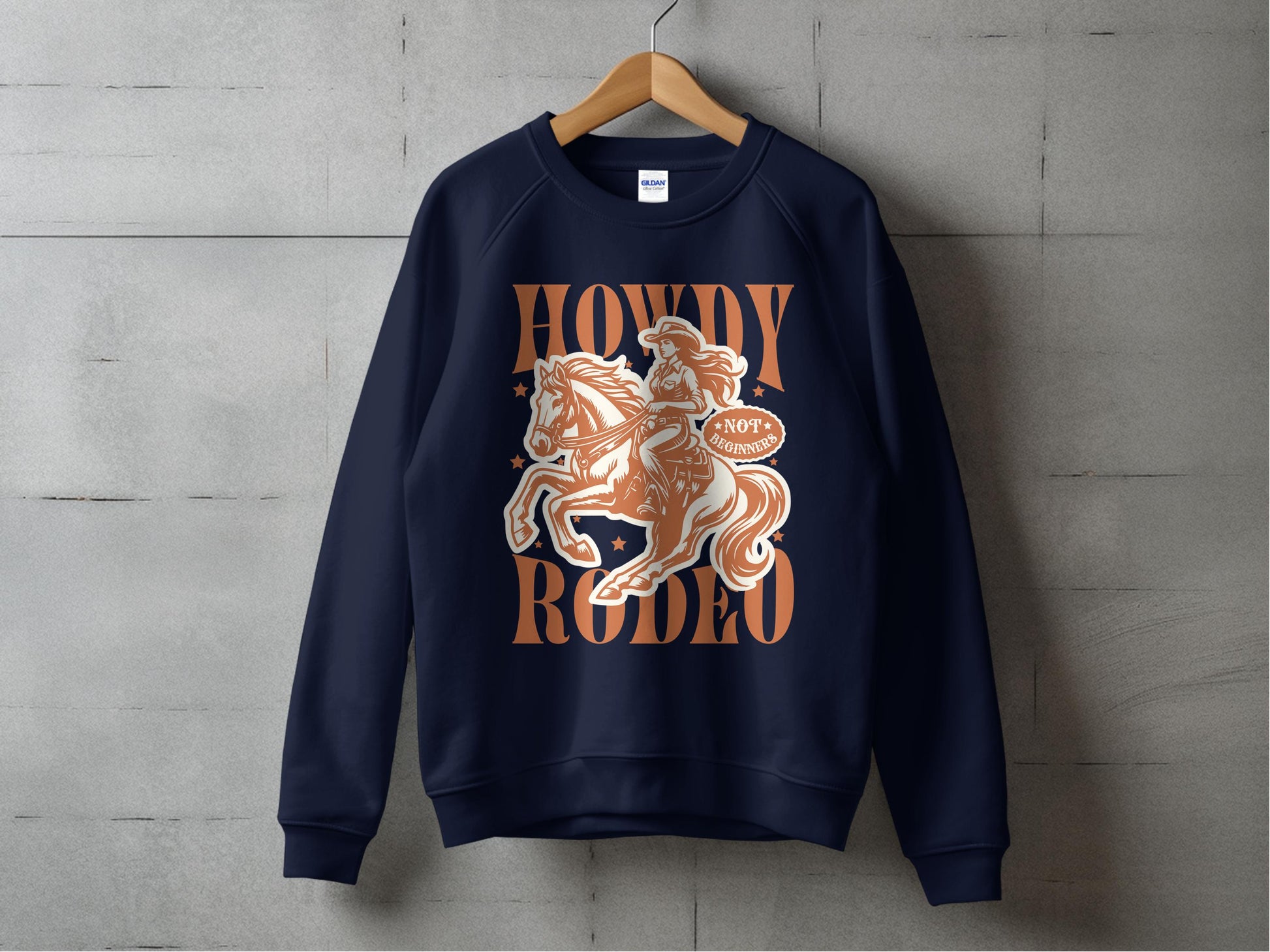 A navy sweatshirt by Garment Graphics hangs against a concrete wall, featuring a cowboy on a bucking horse with Howdy Rodeo in bold print and Not Today, Cowboy in a speech bubble. Its designed for unisex sizing.