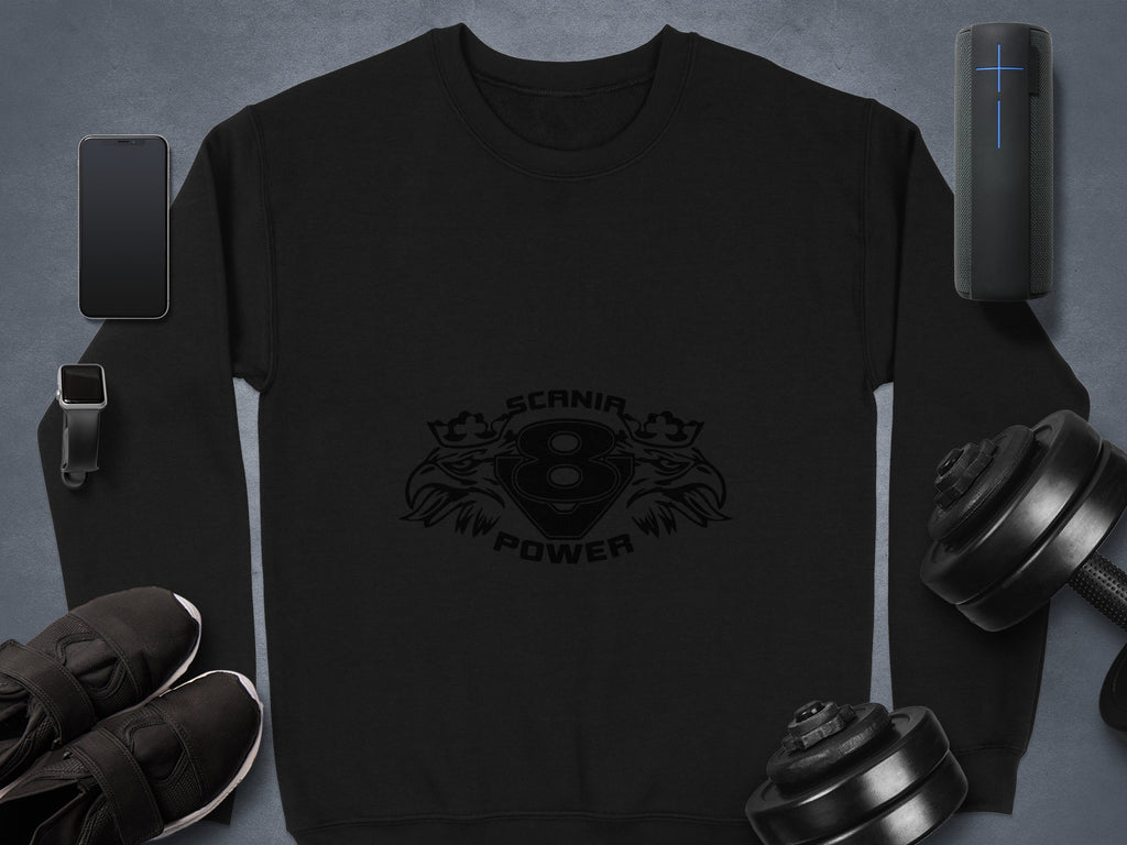 The image features a black Garment Graphics sweatshirt with the Scania Power 8 logo, alongside a smartphone, Bluetooth speaker, smartwatch, sleek black shoes, and two dumbbells set against a gray background.