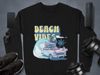 Garment Graphics offers a black graphic sweatshirt featuring a retro pink car with surfboards, palm trees, an ocean wave, and BEACH VIBES in sunny yellow. It’s unisex and pairs well with essentials like a smartphone, smartwatch, Bluetooth speaker, sneakers, and adjustable dumbbells.
